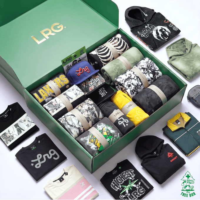 An open green LRG gift box filled with assorted folded apparel and accessories, surrounded by additional clothing items laid out on a white background. Visible brands include LRG on the box and card, Adidas on a black hoodie, and Reebok on a green shirt.