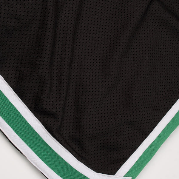 Black athletic shorts with green and white trim on a white background