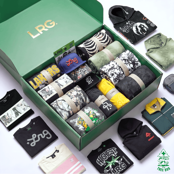 An open green LRG gift box filled with assorted folded apparel and accessories, surrounded by additional clothing items laid out on a white background. Visible brands include LRG on the box and card, Adidas on a black hoodie, and Reebok on a green shirt.